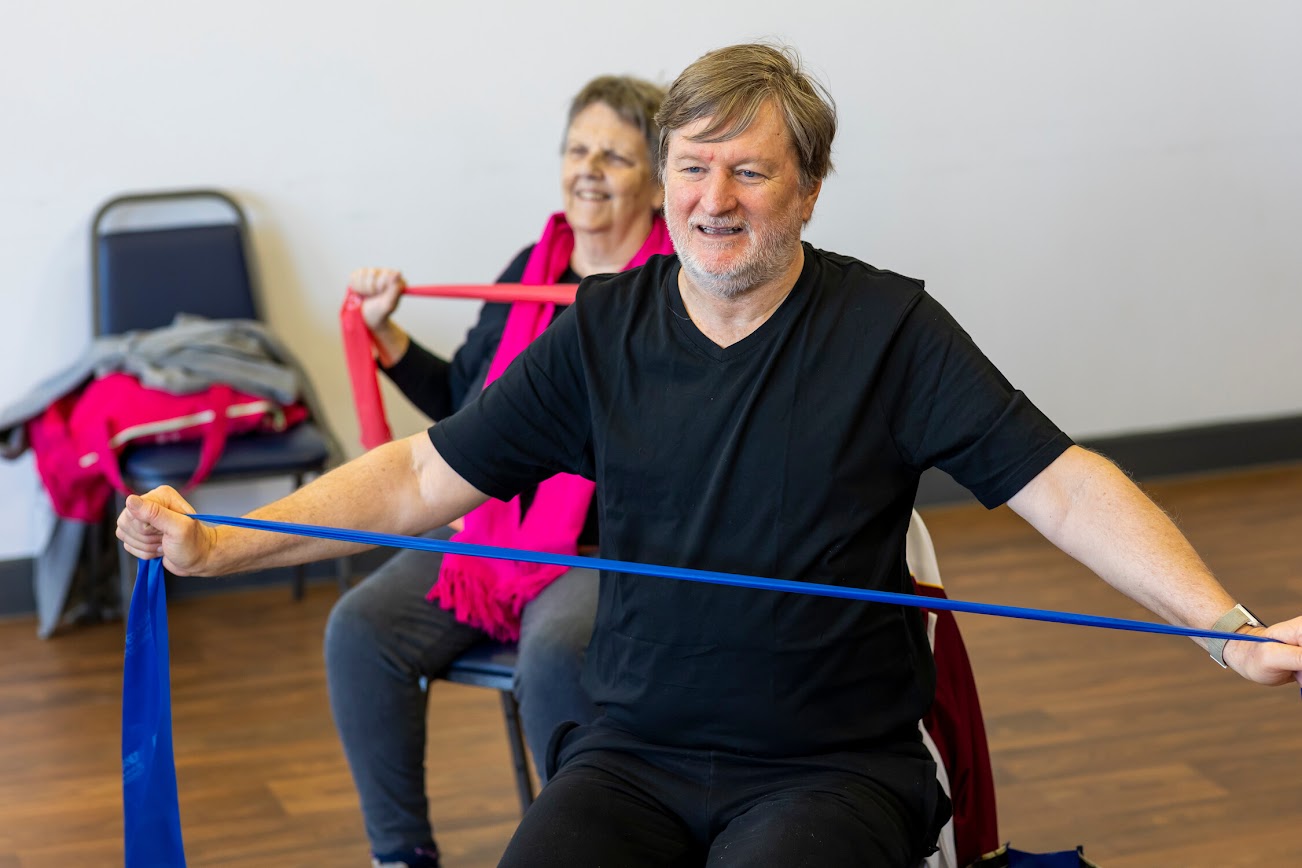 A man and a woman in an exercise class wearing black clothing