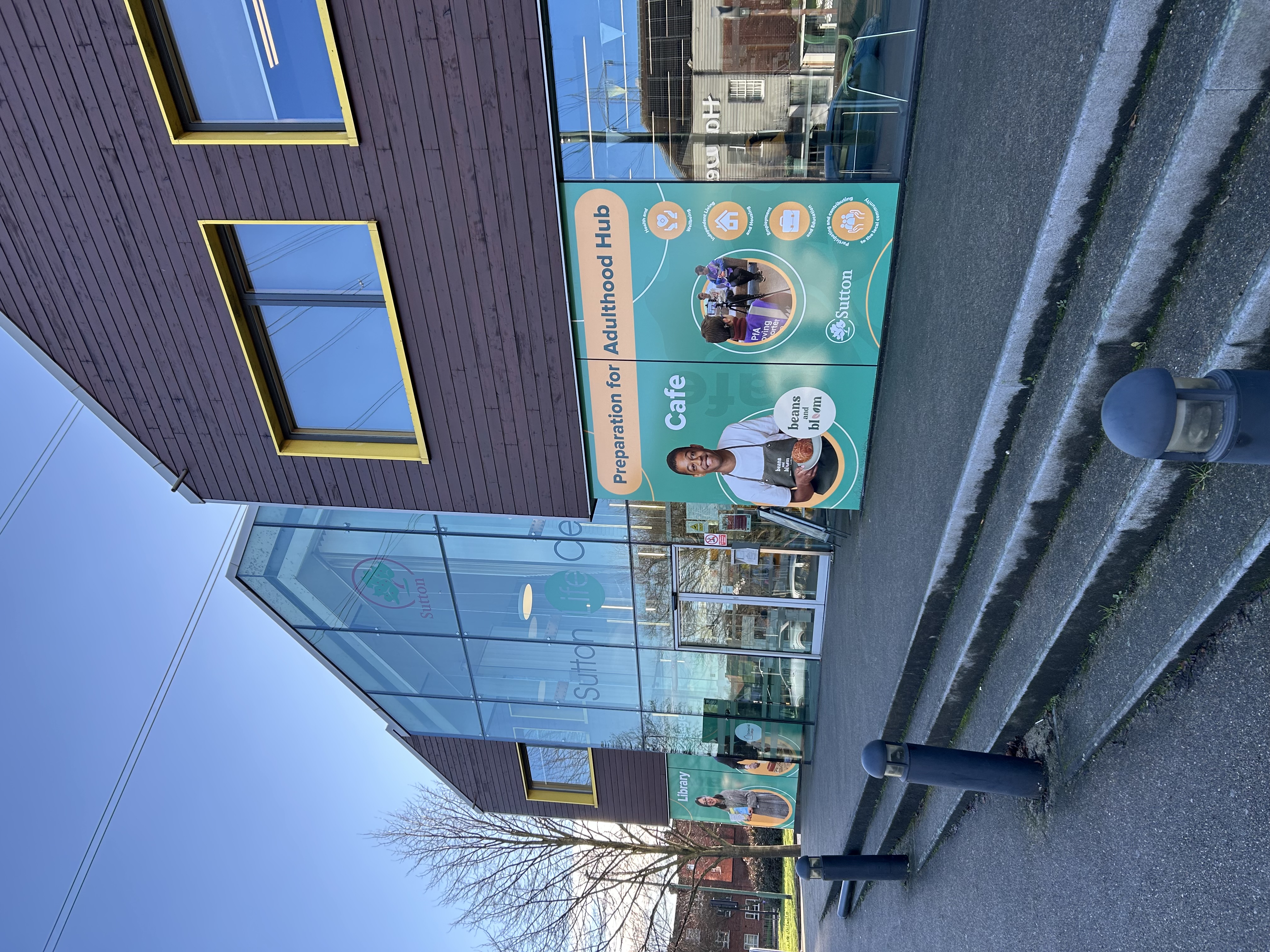 The front of the Sutton Life Centre, from outside. In the foreground there is a banner promoting the Preparation for Adulthood Hub and cafe