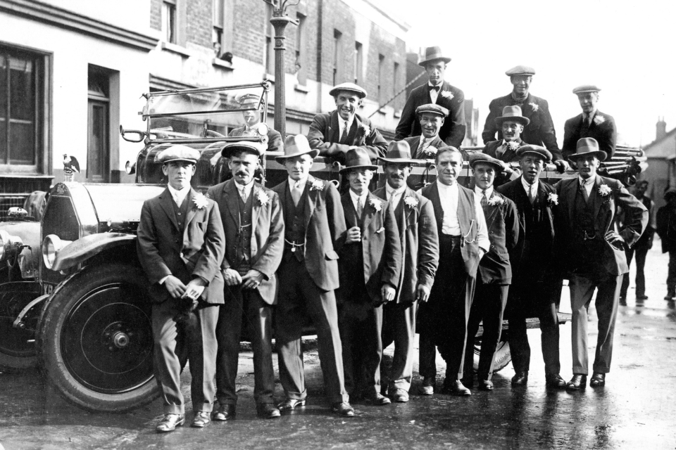 Historic photo of men posing next to a car on the street