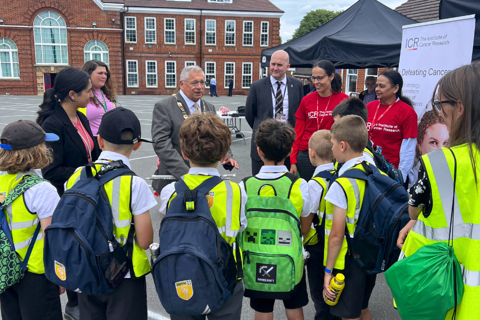 A cluster of school children wearing high-vis jackets looking towards Mayor Cllr Colin Stears