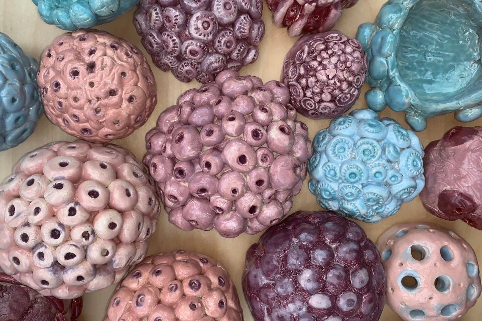 An assortment of coloured clay-based art pieces featuring several bobbles and holes