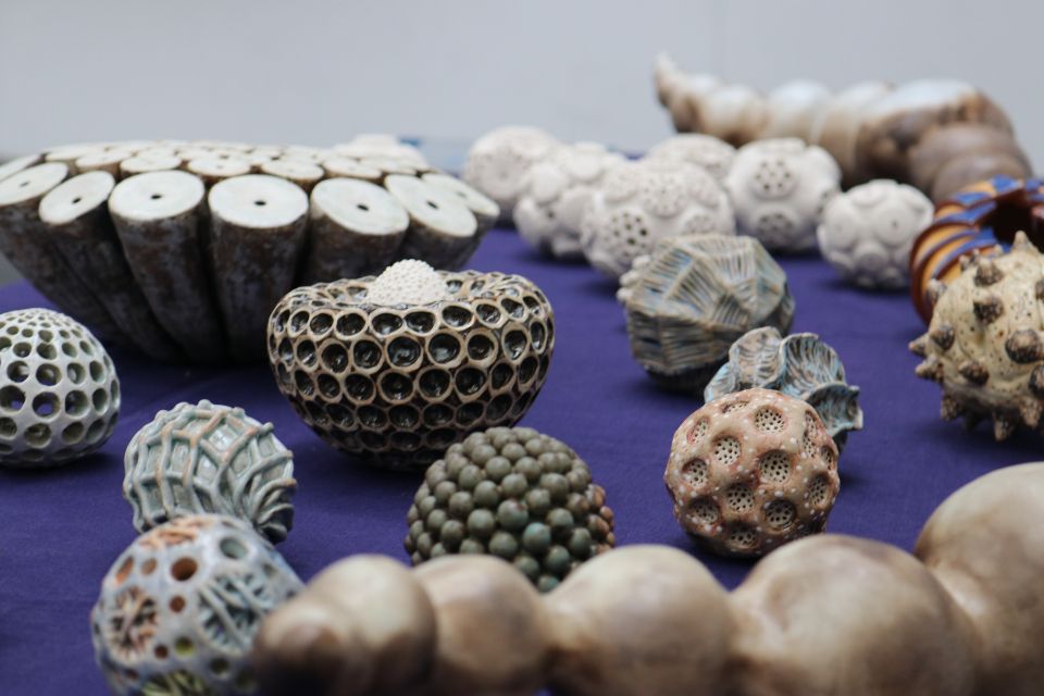An assortment of white, grey and brown clay-based art pieces featuring several bobbles and holes