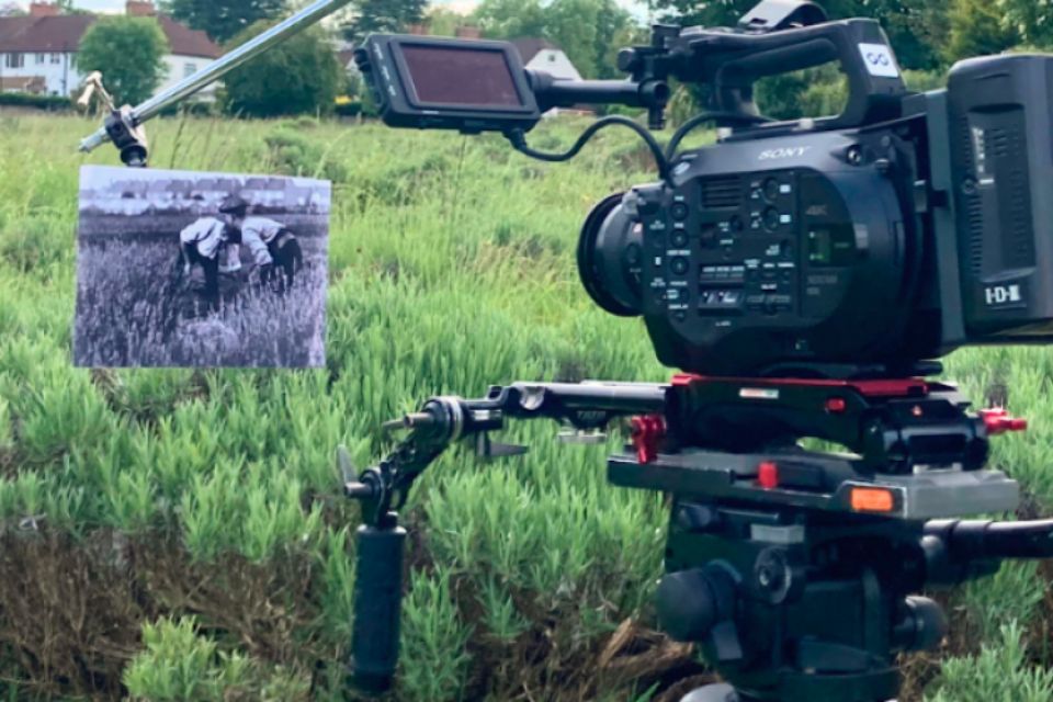 A film camera pointed towards a grassy field