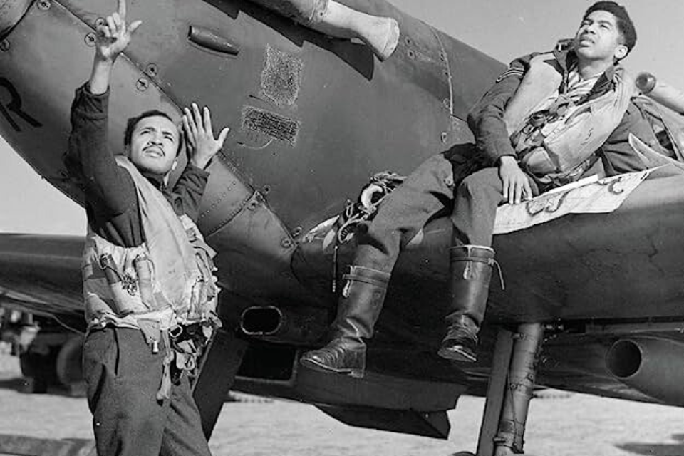 Historic image of two gentleman lounging near a fighter jet