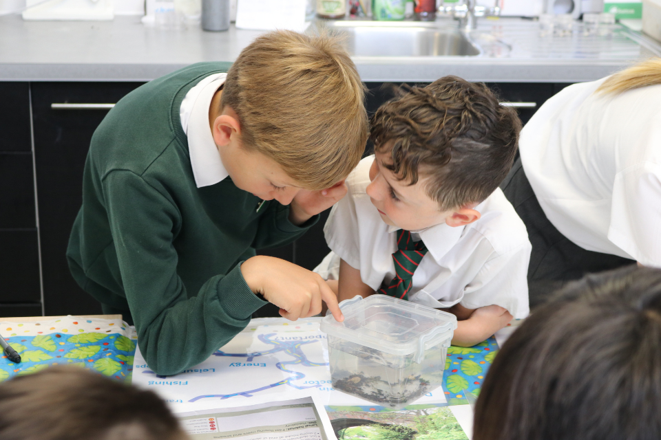 Two Robin Hood pupils looking towards a plastic container