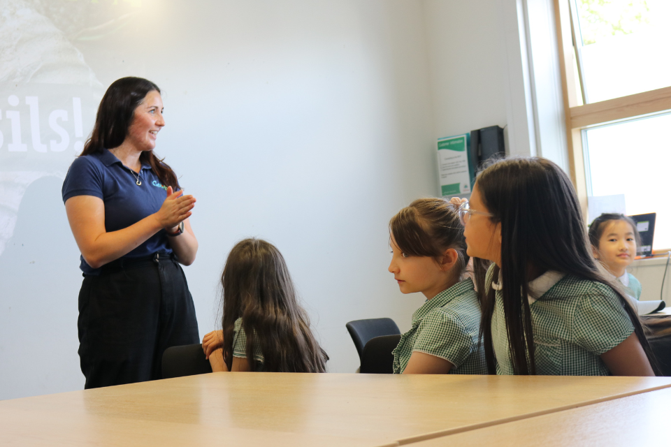 A woman stood in front of primary school children sat at tables